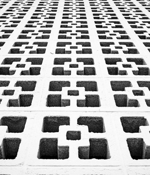 Black and white photo of a modern concrete wall with geometric patterns, showcasing symmetry and abstract design.